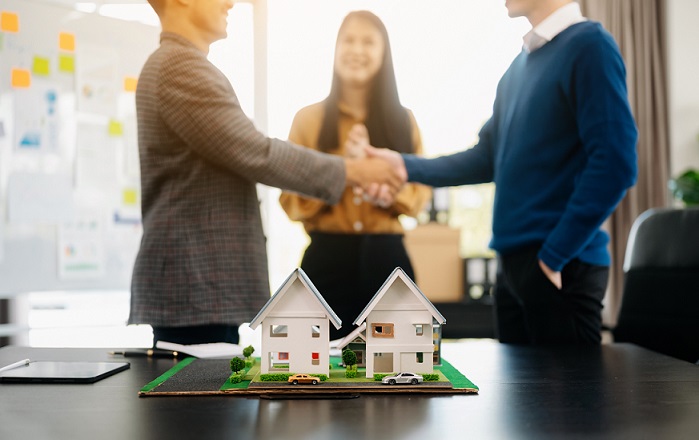 Toronto real estate transaction at Zinati Kay Real Estate Law Firm, showing a handshake over model houses, symbolizing successful property negotiations.